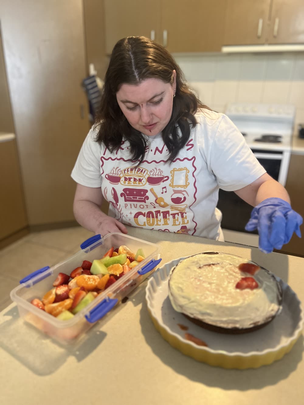 A person preparing fruit and a cake in a home kitchen.