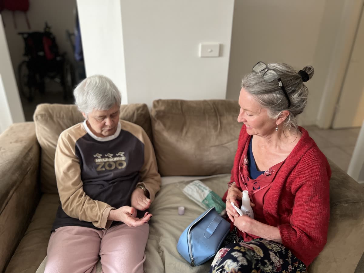 Two people seated together on a sofa with daily care items nearby.